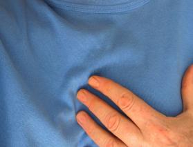 Man in blue shirt holding a hand over his heart