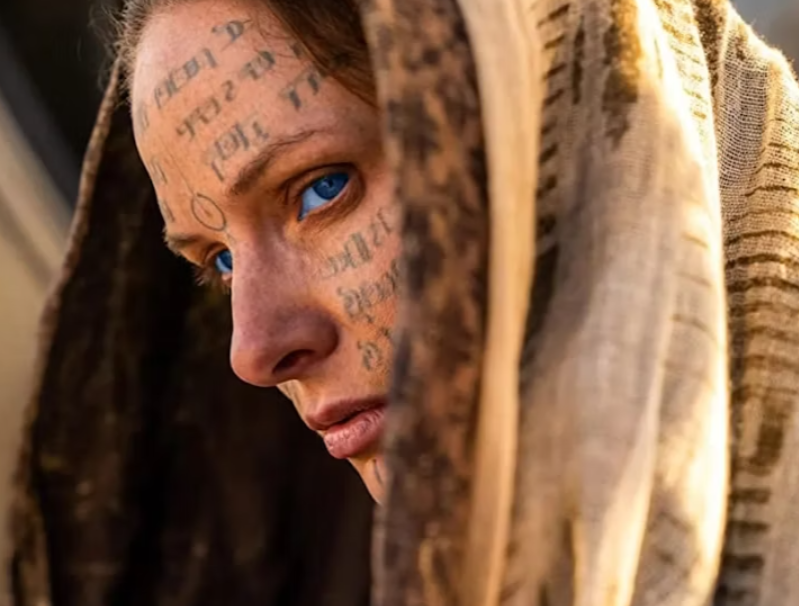 A woman with blue eyes from dune with cryptic language on her face