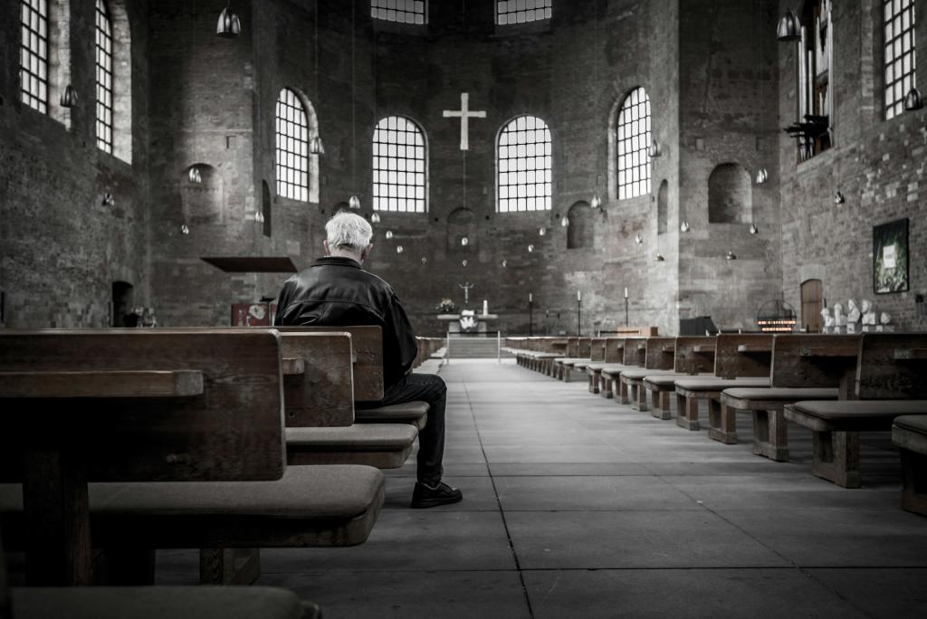 Man sitting alone in an empty church (Black and white photo) 