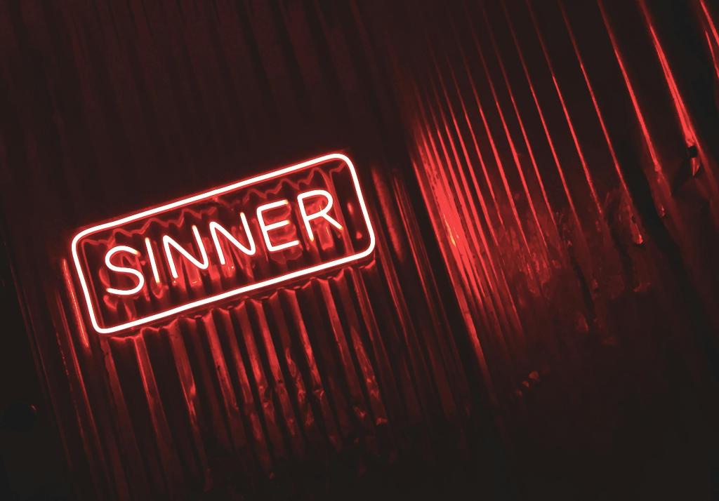 Neon sign of "Sinner" by red drapes