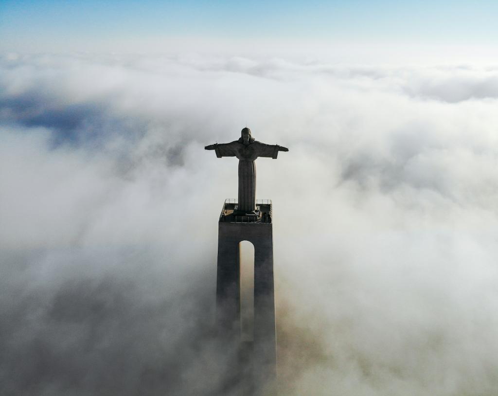 An image of Cristo Rei statue in Lisbon, Portugal, surrounded by clouds.