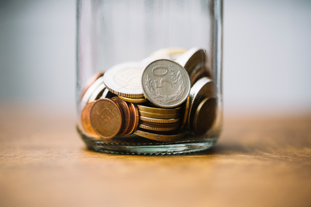 Coins from around the world barely filling a clear jar