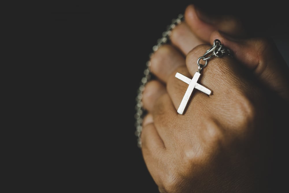 A black woman's hand holding a Rosary