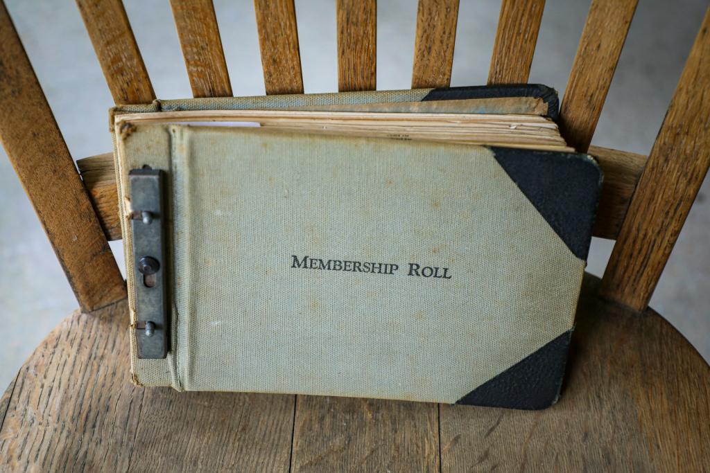 A close-up of an older book titled "Membership Roll" sitting on a wooden chair
