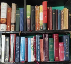 Two book shelves full of bible versions including the Passion Translation