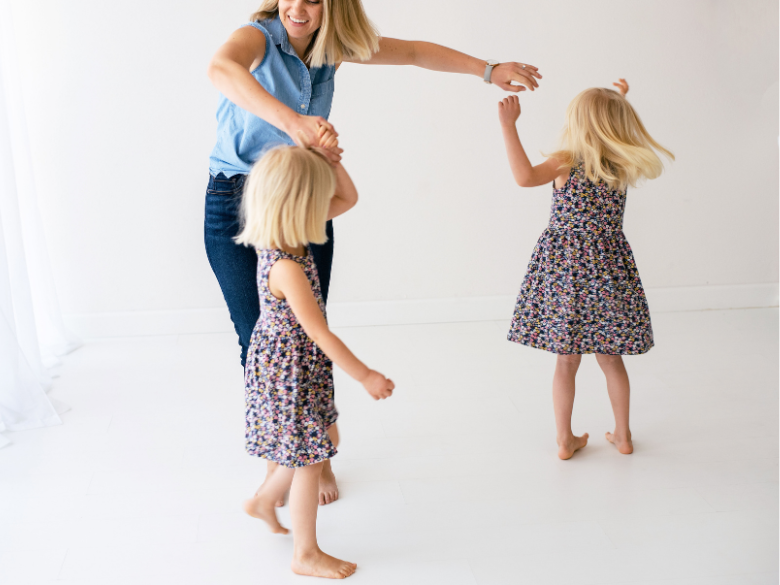 Mom twirling and dancing with two young girls.