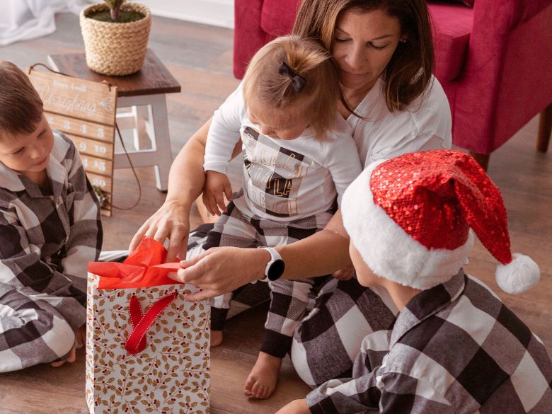 Family in matching pajamas unwrapping a Christmas gift