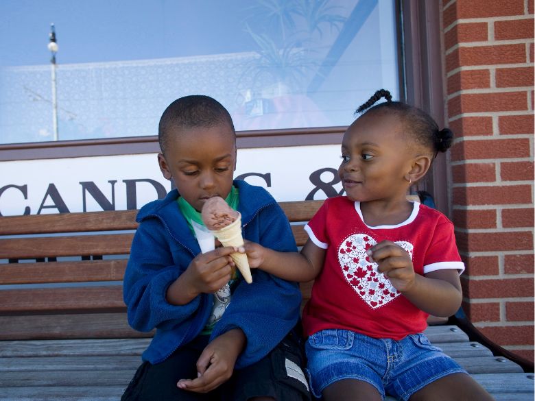 little girl sharing chocolate ice cream cone with little boy