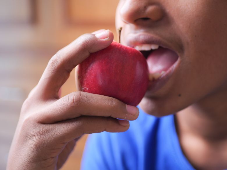 child in a blue t-shirt eating an apple