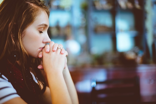 A teen girl clasps her hands in prayer