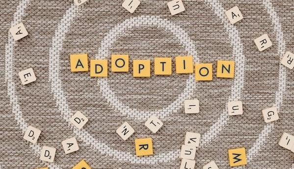 Scrabble letters scattered about circular designs with "adoption" spelled out in the middle.