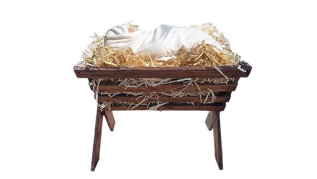 Manger holds hay and a baby wrapped in white cloths.
