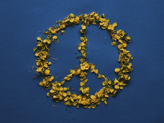Peace symbol made with yellow petals on a blue background