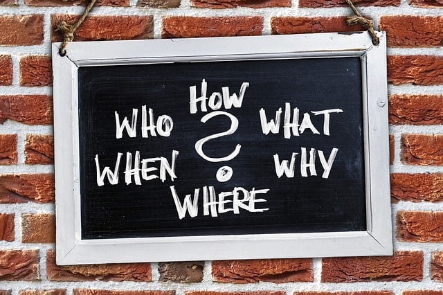 Blackboard set up on brick wall with who, what, why, where, when written on it