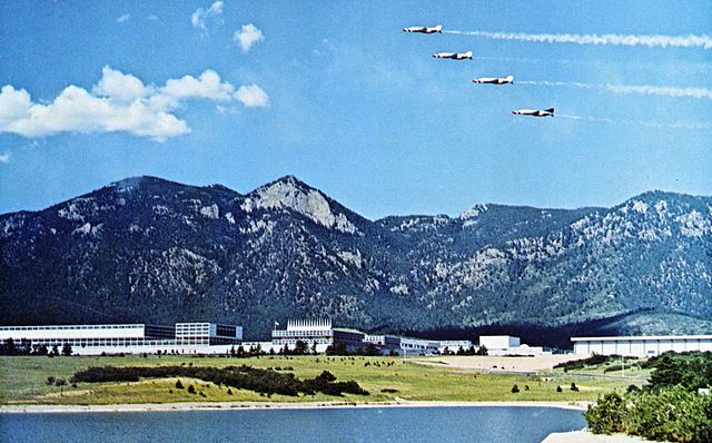 View of USAF Academy from a distance with mountains in the background and planes in the air