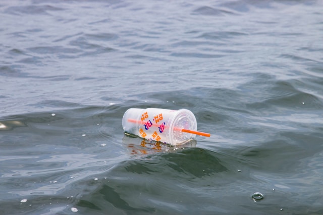 Empty clear plastic cup with lid and straw floats in the water