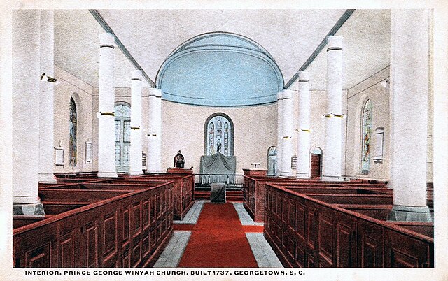 Interior of church looking down the aisle towards the front with box pews on either side of the aisle