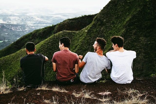 Four young guys sitting with their backs to the camera with a view of the mountains before them