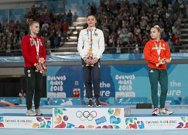 Three athletes standing on the tiered podium wearing their medals