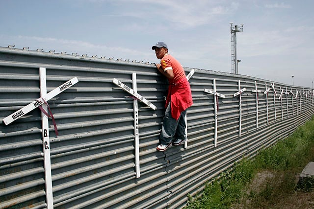 Man climbing a wall to enter the US illegally from Mexico