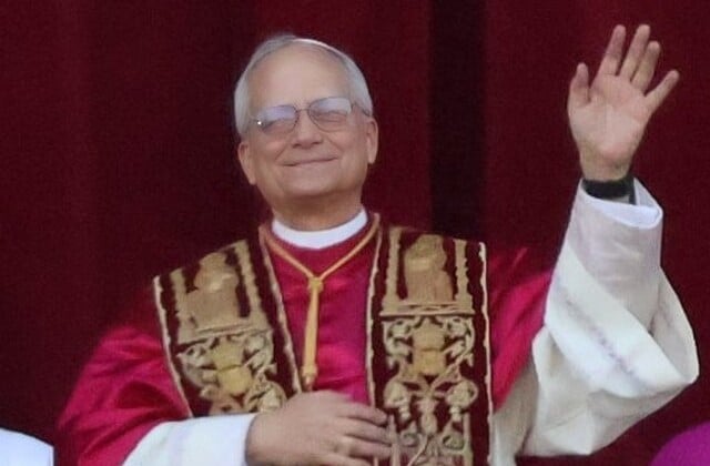 View of Pope Leo XIV from the waist up wearing papal vestments with his right hand raised in a wave