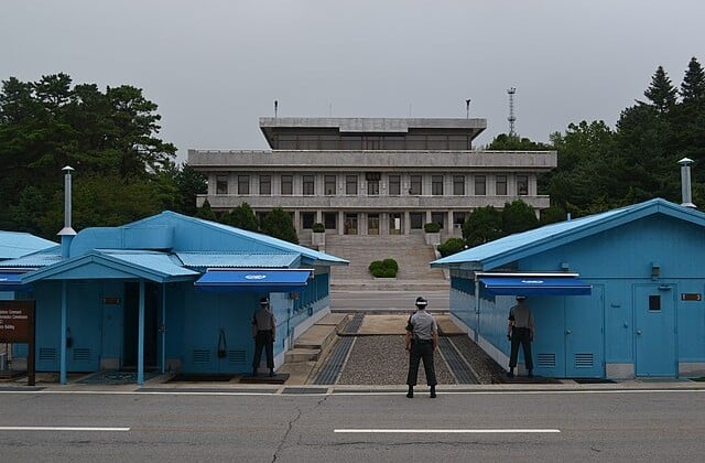 View across the DMZ from the South Korean side to North Korean building with South Korean soldier on guard viewed from behind