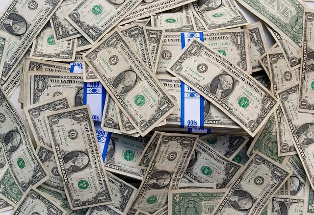 View from overhead of numerous dollar bills, some of which are stacked together with a blue and white band