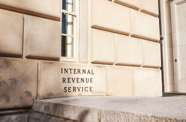View of a light-colored stone building's side with a sign identifying it as the Internal Revenue Service.