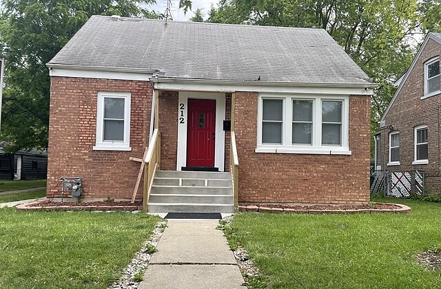 Front view of small brick house with sidewalk and steps up to the front door where Pope Leo lived growing up