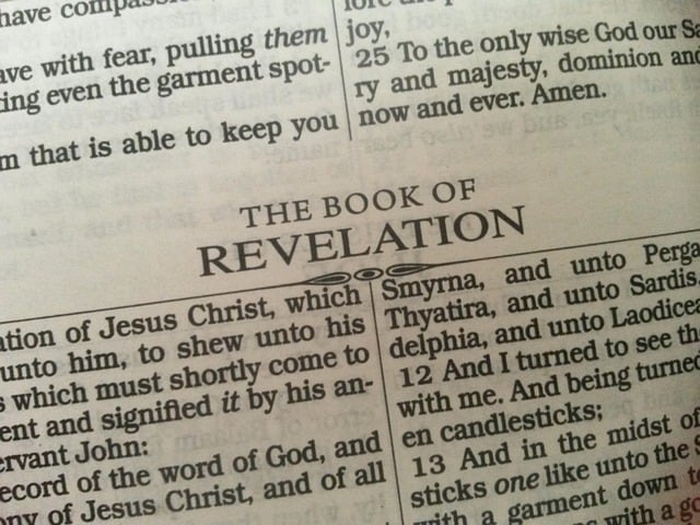 Close up shot of a Bible page opened to the beginning of Revelation