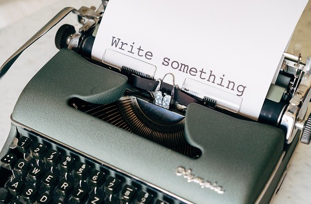 Green typewriter with a piece of paper in it with the words "Write something" typed on it.