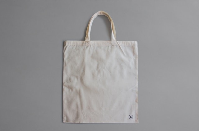 Plain off-white tote bag on a gray background