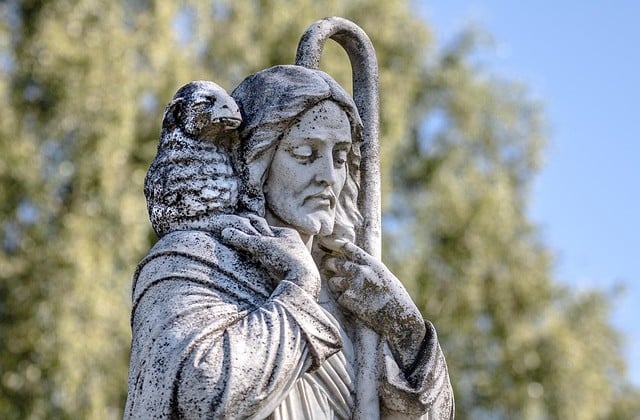 Close up view of top of statue of Jesus holding a staff and carrying a lamb around His neck