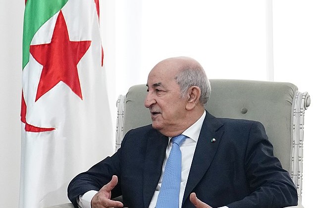 View from waist up of Algerian President seated and talking and using his hands 
