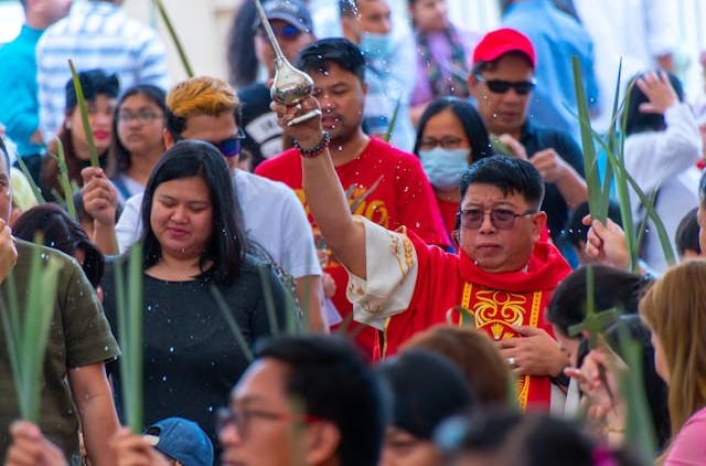 Traditional Palm Sunday procession with Asian people both clerical and lay proceeding down a street with some holding palm branches