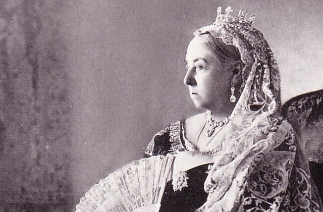 Black and white picture of Queen Victoria seated holding a fan and wearing a crown