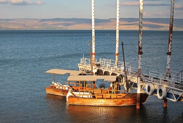 View of two boats docked on the Sea of Galilee with mountains in the distance