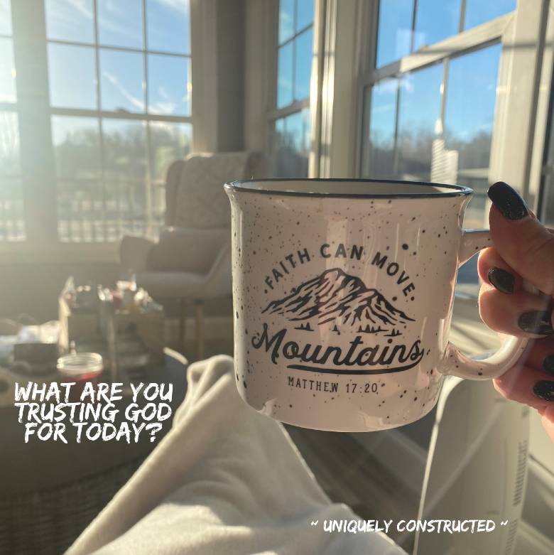 Coffee mug with, "Faith can move mountains" and the question : What are you trusting God for? with windows and sunshine in the background..