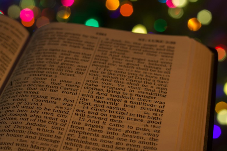 Bible open to the Christmas story with Christmas lights in the background.