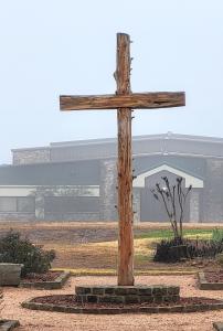 This image shows a wooden cross with fog in the background.