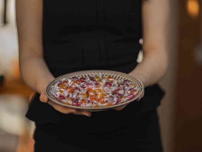 Woman in Black Tank Top Holding Plate with Candies