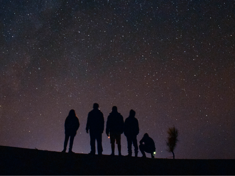 five people looking up at a starry night sky
