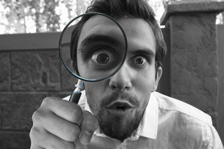 Man peering through magnifying glass.