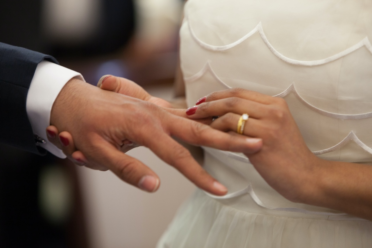 bride places wedding ring on husband's finger