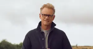 Steven Curtis Chapman, a middle-aged man, standing in front of a gray sky wearing a jacket. The main image for his July 2024 single, "Do it Again"