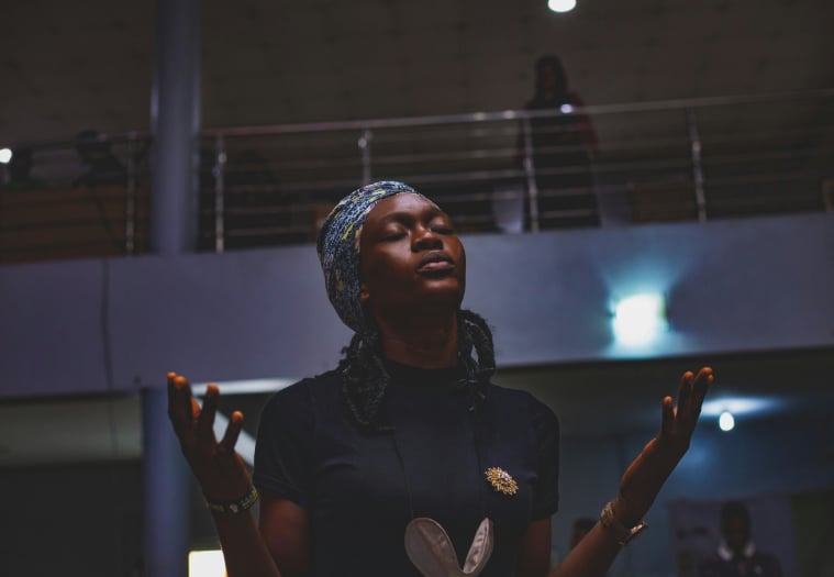 A woman adoring God in prayer during a church service.