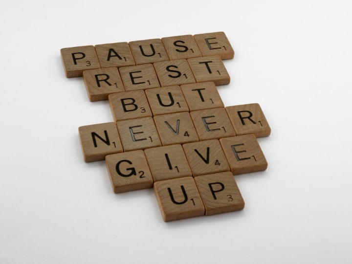 Never give up is a message represented with scrabble letters in this picture. It's okay to pause and rest but not to quit.