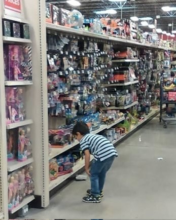Image shows young boy in grocery store choosing a toy car