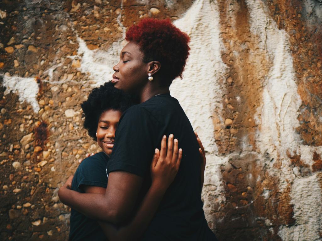 Woman of color holding her middle school daughter.