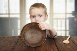 Cute blonde boy shows empty plate